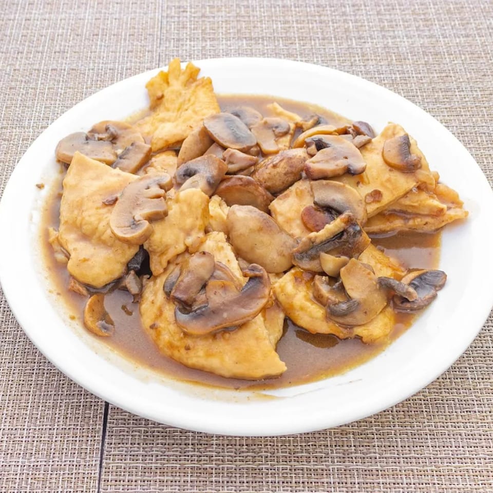Chicken and mushrooms in a brown sauce, served on a white plate.